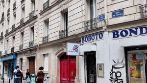 Fasad bangunan klasik di Paris dengan plang bertuliskan BOBOTO di atas sebuah pintu merah
