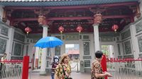 Pengunjung memegang payung biru berdiri di depan gerbang Vihara Satya Budhi Bandung yang megah.
