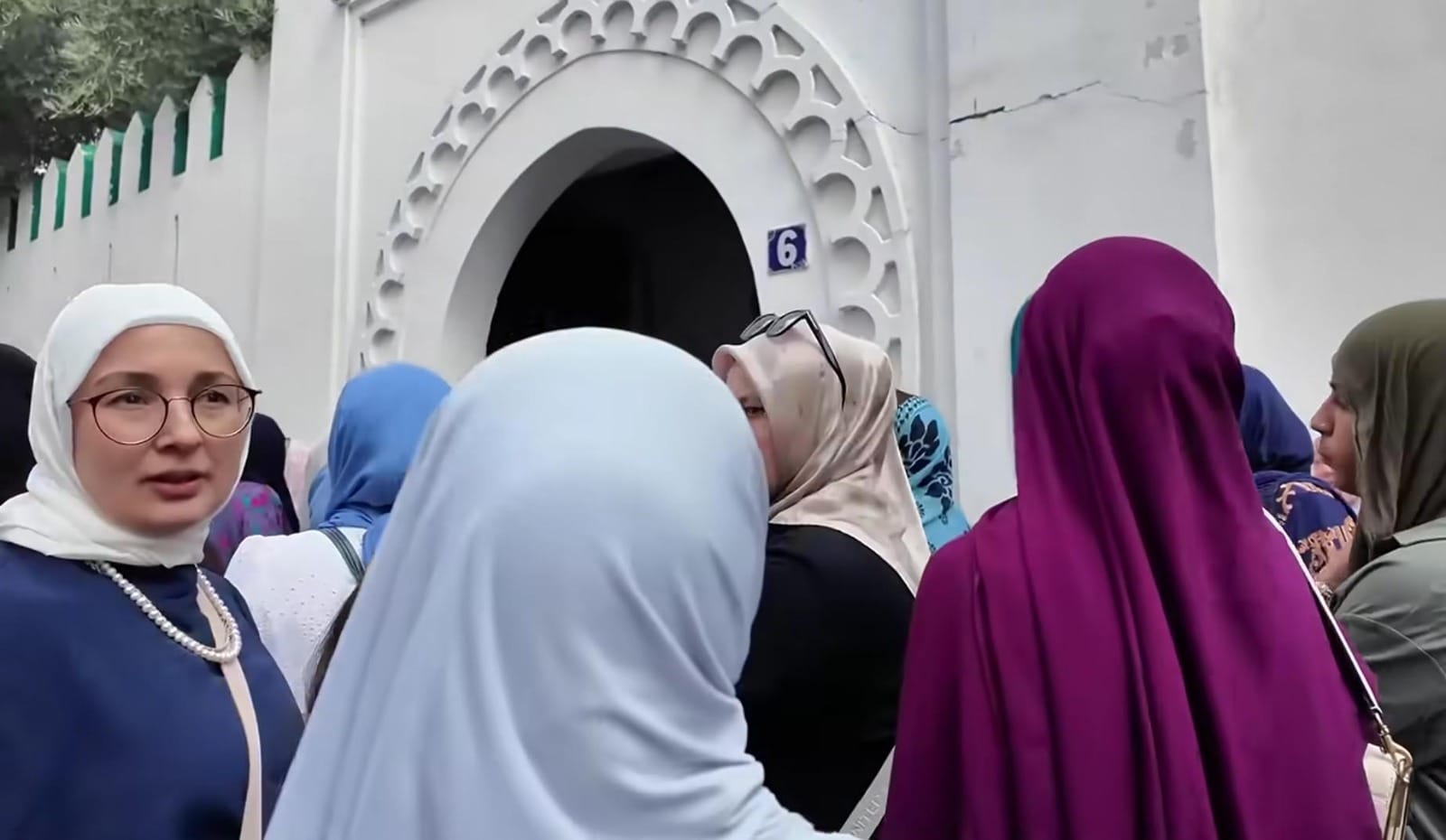 KOLOM ZIQWAF EDISI 216 Sekelompok perempuan Muslim berhijab berkumpul di depan pintu masuk bangunan bercat putih dengan ornamen khas.